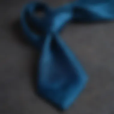 A close-up of a peacock blue tie against a textured fabric background